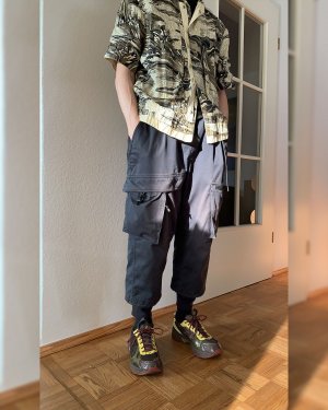 One person in a techwear outfit consisting of Stone Island Shadow Project shorts and Nike ACG Woven Cargo Techwear pants with Asics sneaker