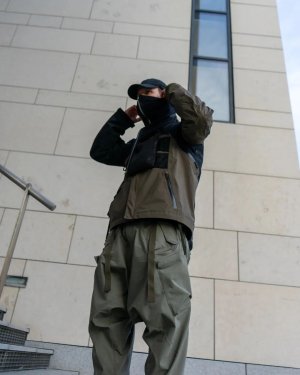 Techwear.Germany aka Janek next to a big futuristic building in Copenhagen in a techwear outfit consisting of North Face Cap, ACRONYM NG4, ACRONYM J1WTS-GT techwear jacket, ACRONYM P30A-DS techwear pants and Asics Gel Nimbus9 shoes