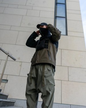 Techwear.Germany aka Janek neben einem großen futuristischen Gebäude in Kopenhagen in einem Techwear Outfit bestehend aus North Face Cap, ACRONYM NG4, ACRONYM J1WTS-GT Techwear Jacke, ACRONYM P30A-DS Techwear Hose und Asics Gel Nimbus9 Schuhen